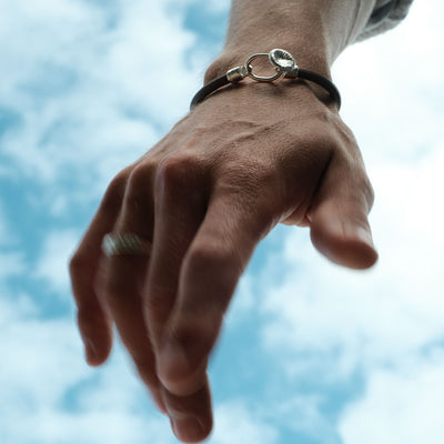 Elegant läderarmband med knappkorall mot himlen