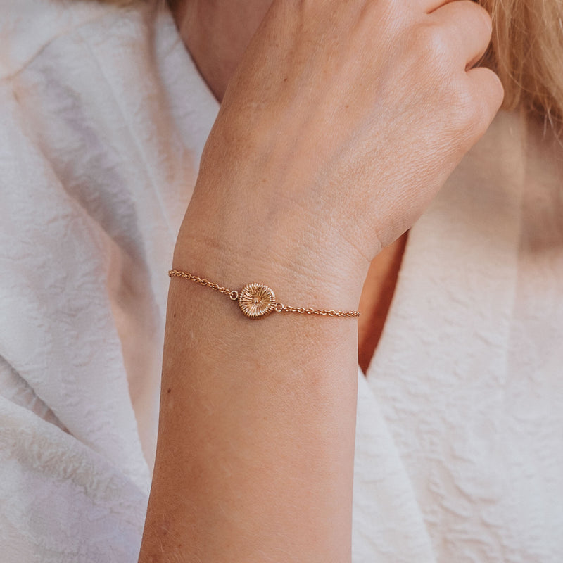 Knappkorall armband i guld på handled