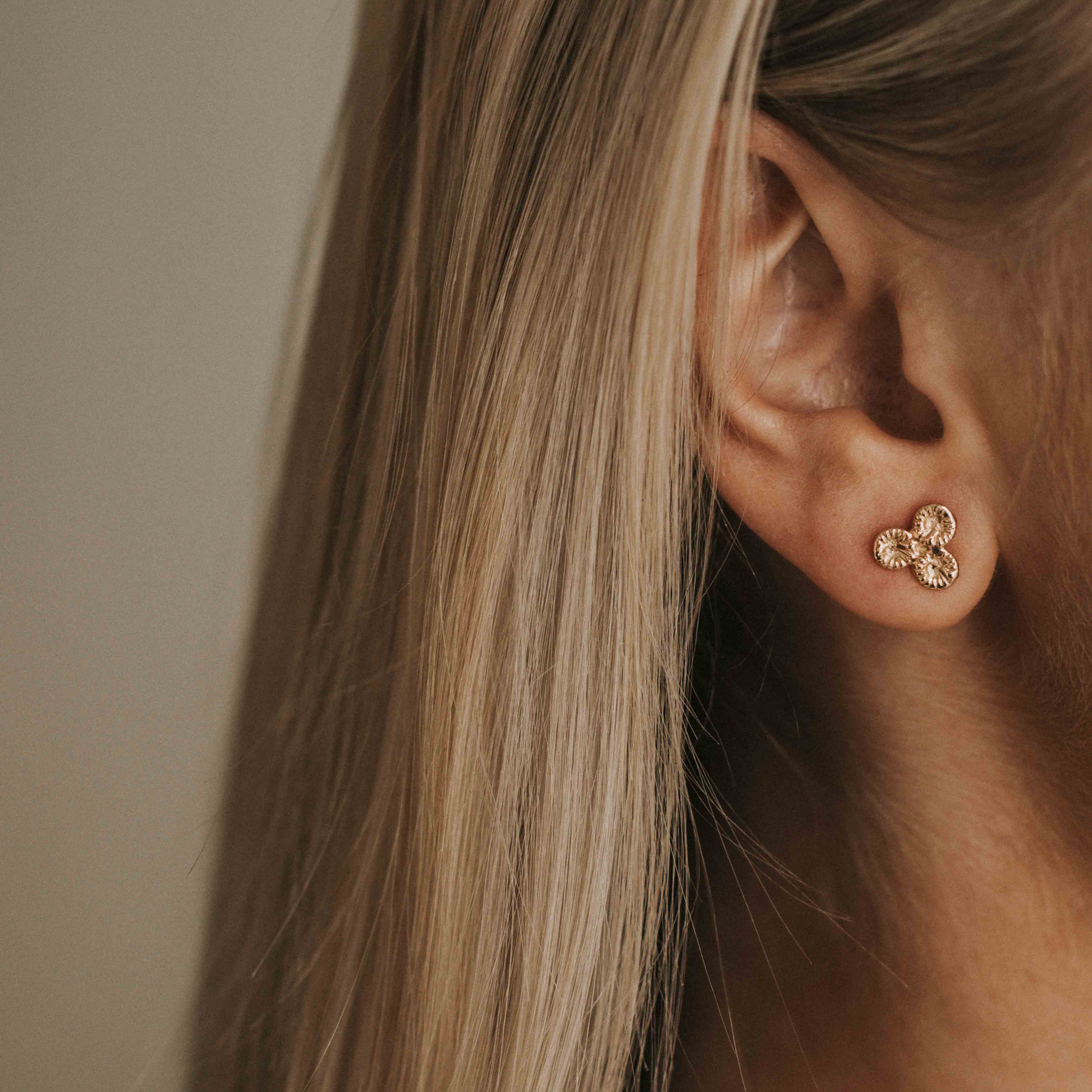 Knappkorall örhängen i guld på örat