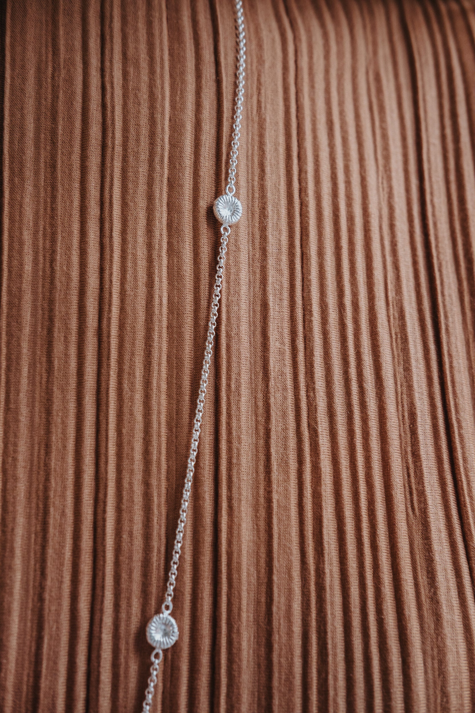 Närbild av knappkorallhalsband på brun klänning