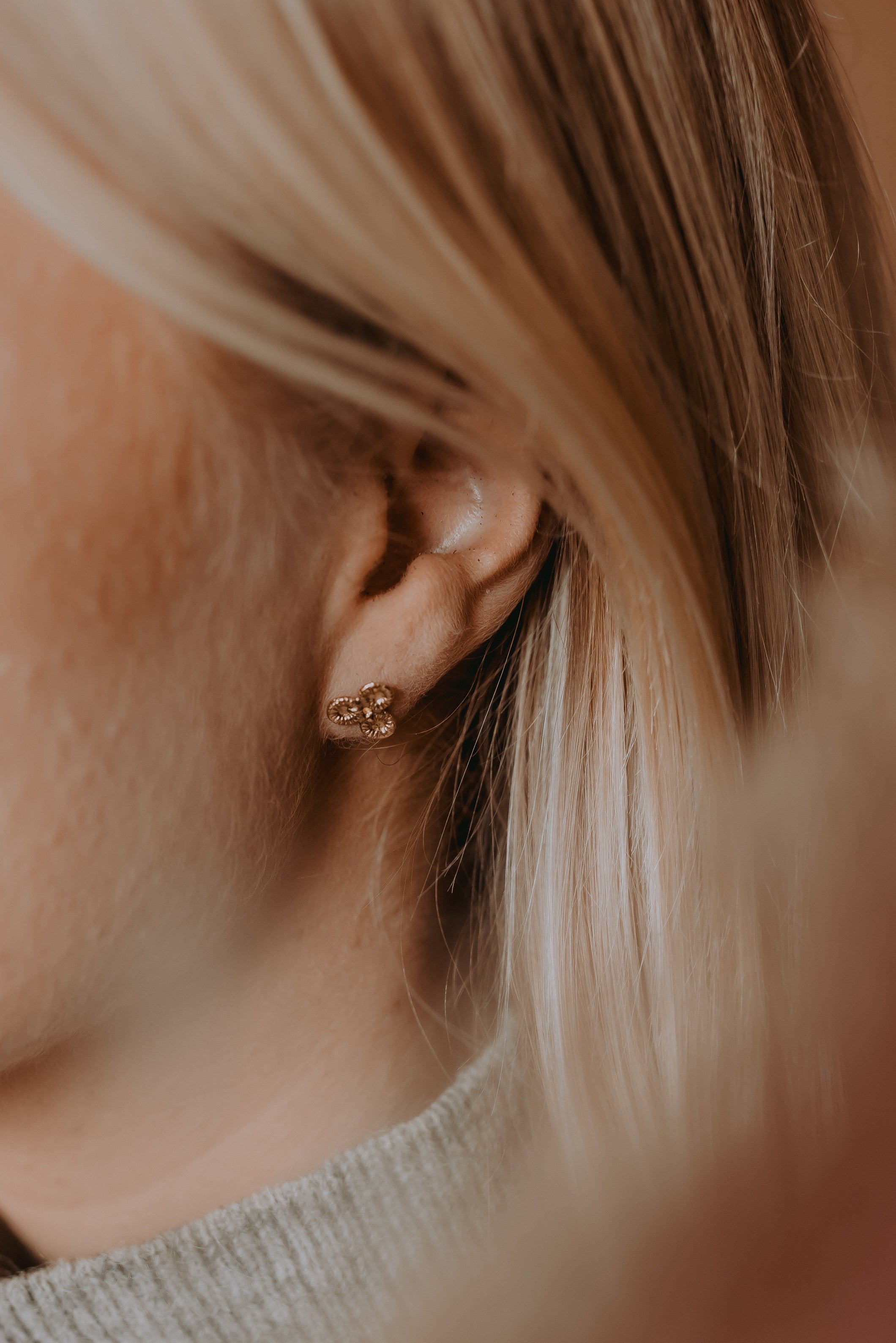 Knappkorall örhängen i guld på kvinnas öra