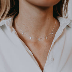 Silverhalsband med droppar på vit skjorta.