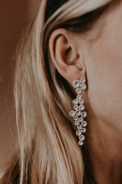 Knappkorall örhänge på örat, elegant design