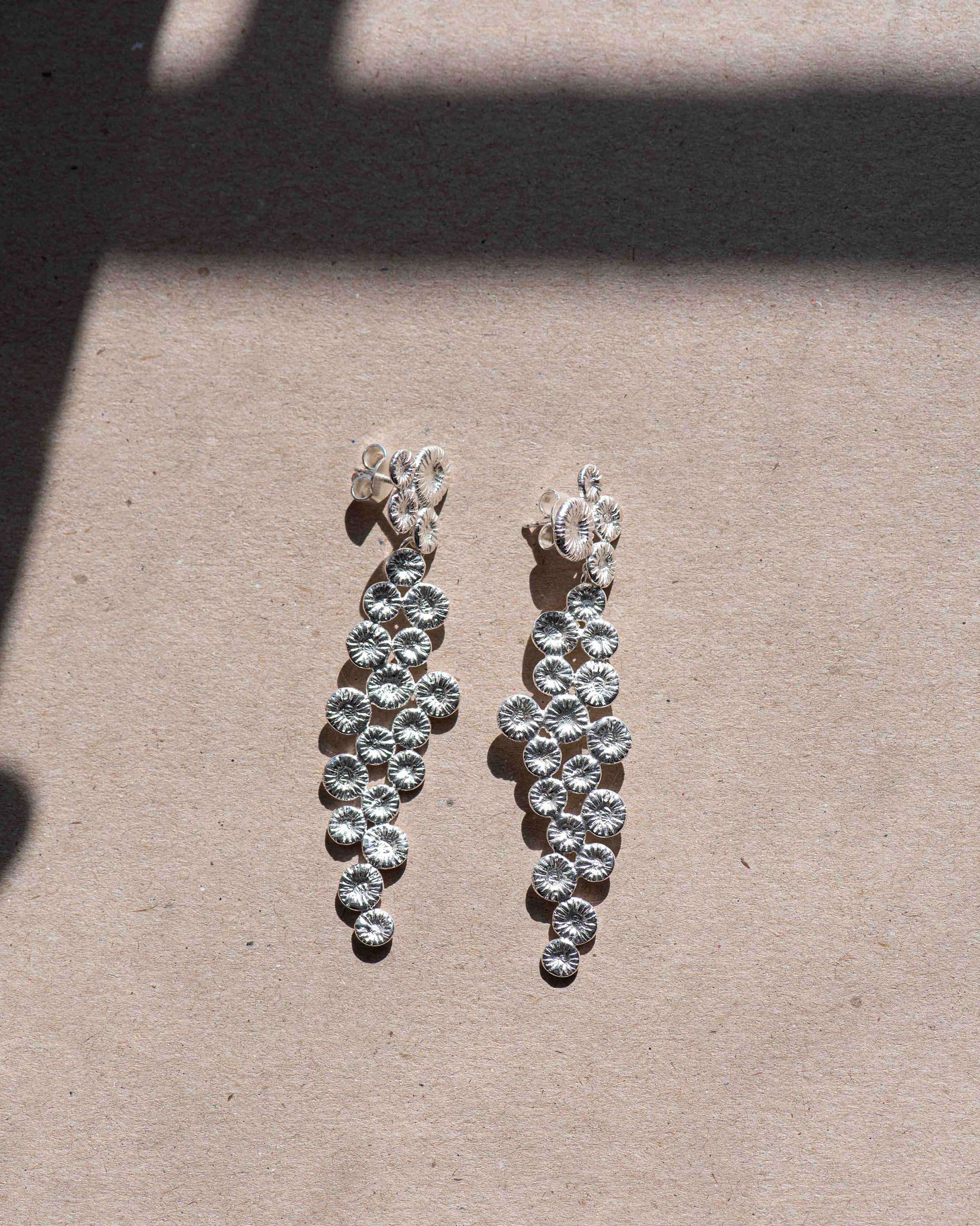 Knappkorall örhängen på beige bakgrund